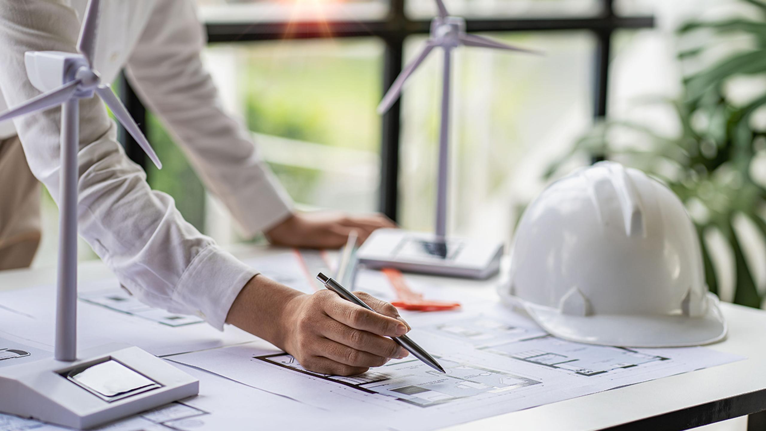 Ontwerptafel met plannen en schaalmodellen windmolens.
