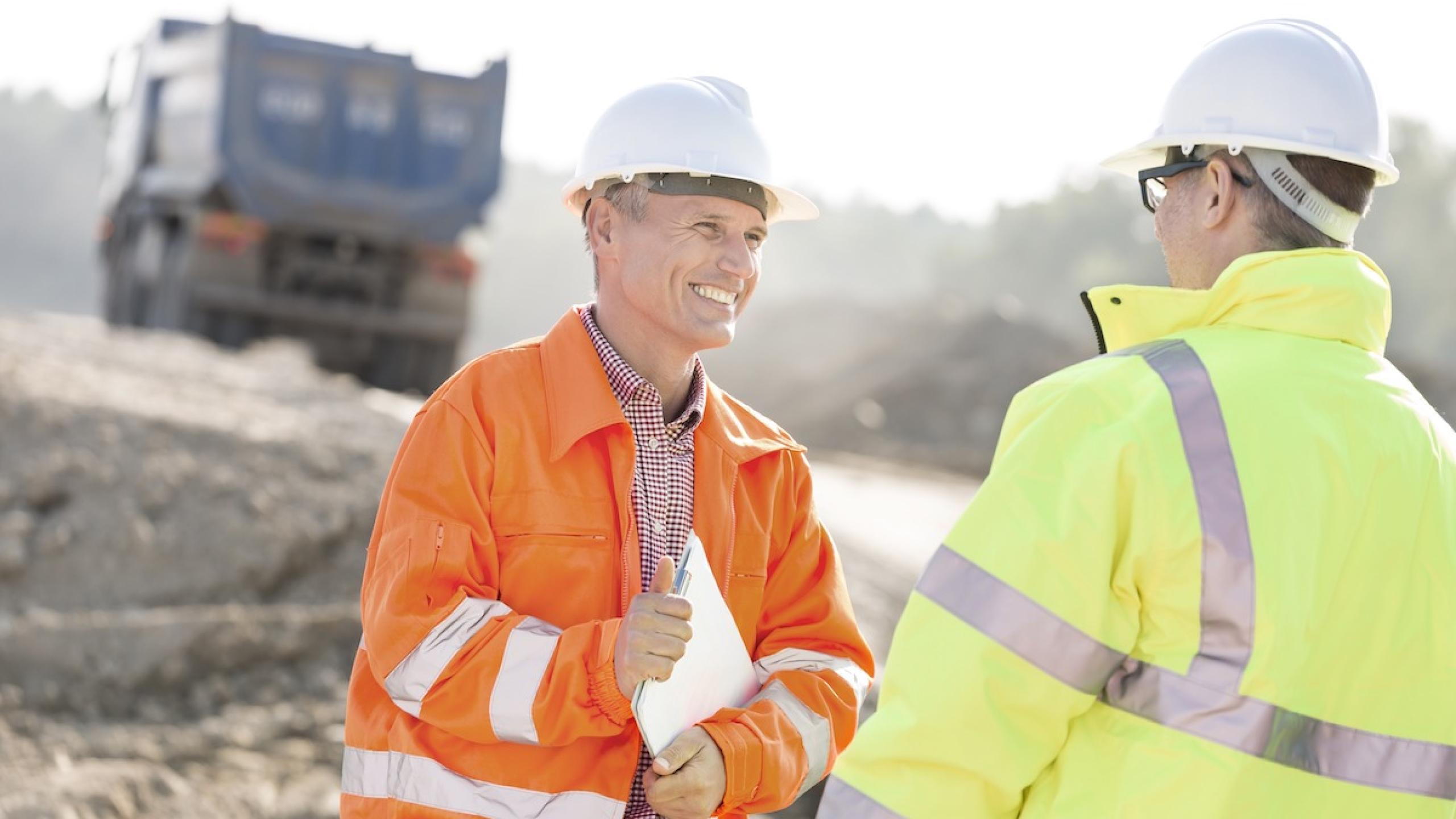 Twee mannen in fluohesjes op een werf.